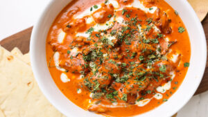 white bowl with butter chicken and naan